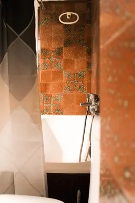 a bathroom with a toilet and a tile wall at 50 Steps Apart Metro Neos Kosmos in Athens