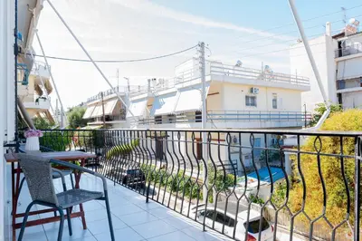 a balcony with a table and a chair and a building at Cozy Greek Apartment in Athens