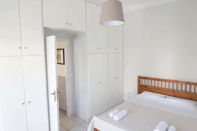 a bedroom with white cabinets and a bed with white towels at Cozy Greek Apartment in Athens
