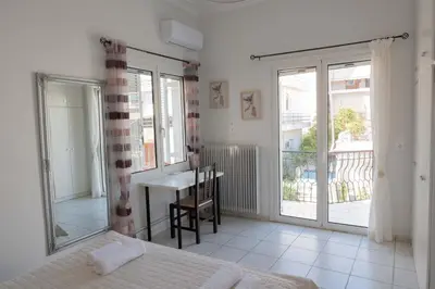 a bedroom with a bed and a desk and windows at Cozy Greek Apartment in Athens