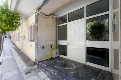 an empty building with white doors and a sidewalk at Pagrati Cozy Retreat in Athens