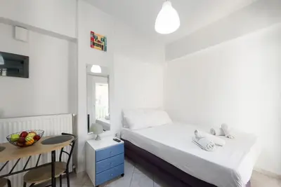 a white bedroom with a bed and a table at Pagrati Cozy Retreat in Athens