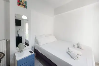 a white bedroom with a bed and a mirror at Pagrati Cozy Retreat in Athens