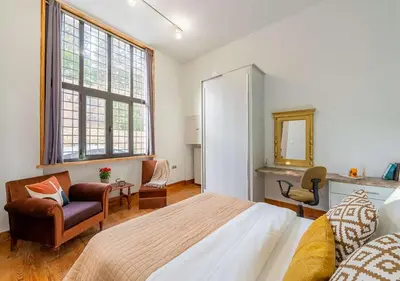 a bedroom with a bed and a chair and a mirror at Spacious 2-Bdrm Apt at Filopappou hill in Koukaki! in Athens