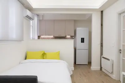a bedroom with a white bed and a refrigerator at Cosy Athens Downtown Apartment in Athens