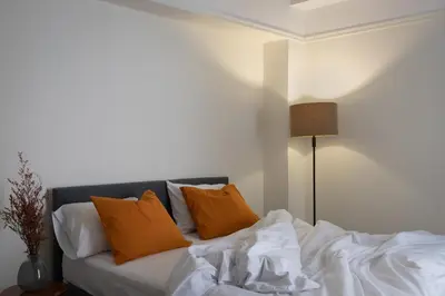 a bed with white sheets and orange pillows at Cosy Athens Downtown Apartment in Athens