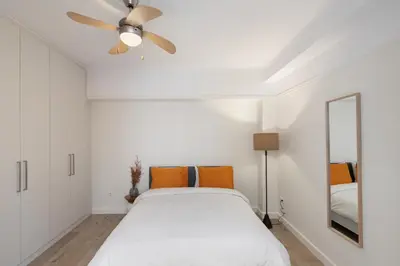 a white bedroom with a bed and a ceiling fan at Cosy Athens Downtown Apartment in Athens