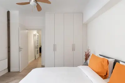 a white bedroom with a bed and a ceiling fan at Cosy Athens Downtown Apartment in Athens
