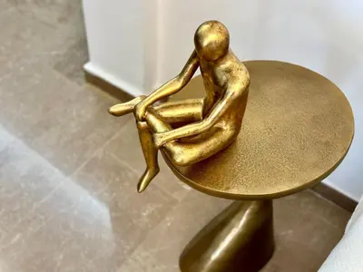 a bronze statue of a person sitting on a table at Elaia Luxury Selections - Emerald in Athens