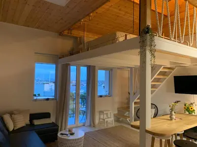 a room with a loft bed and a living room with a table at Zefi's Loft - Sea View in Piraeus in Piraeus