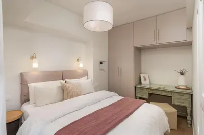 a white bedroom with a large bed and a desk at Modern apartment at Edem beach in Athens