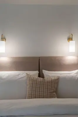 a bed with white pillows and two lights above it at Modern apartment at Edem beach in Athens
