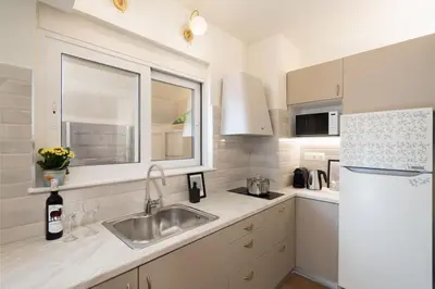 a white kitchen with a sink and a refrigerator at Modern apartment at Edem beach in Athens