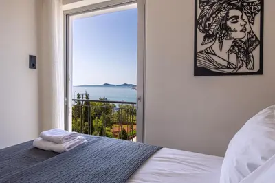 a bedroom with a window with a view of the ocean at Era Suites Lagonisi in Kalívia Thorikoú