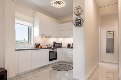 a kitchen with white cabinets and a window at Era Suites Lagonisi in Kalívia Thorikoú