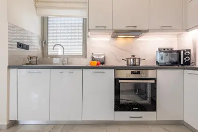 a kitchen with white cabinets and a sink and a microwave at Era Suites Lagonisi in Kalívia Thorikoú