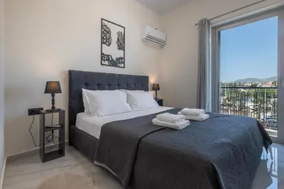 a bedroom with a bed and a large window at Era Suites Lagonisi in Kalívia Thorikoú
