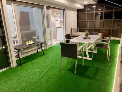 a living room with green carpet and a table and chairs at Terrace Garden Close To Sea in Athens