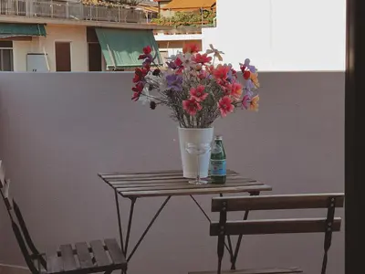a vase of flowers on a table next to a chair at Have a Rest Netflix, Nespresso in Athens