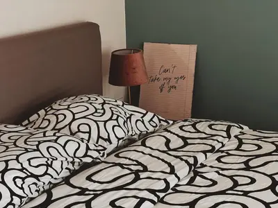 a bed with a black and white comforter and a lamp at Have a Rest Netflix, Nespresso in Athens