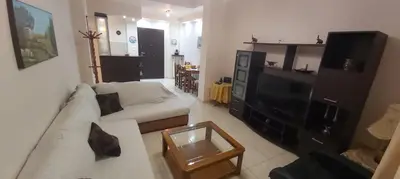 a living room with a white couch and a tv at Styl Apartment in Athens