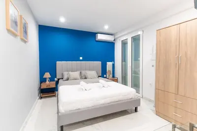a bedroom with a blue accent wall and a bed at AIOLOS centre plateia nea smyrni in Athens
