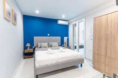 a bedroom with a large bed with a blue wall at AIOLOS centre plateia nea smyrni in Athens