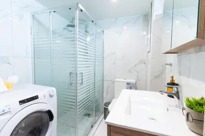 a washing machine in a bathroom with a glass shower at AIOLOS centre plateia nea smyrni in Athens
