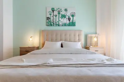 a bedroom with a white bed with a painting above it at Koukaki Gem Chic Apt near Acropolis in Athens