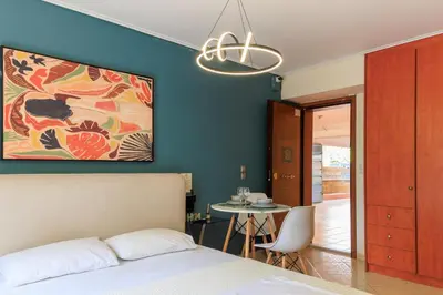a bedroom with a bed and a table and a chandelier at Aiolos GLYFADA super lux apartment in Athens