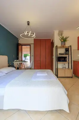 a bedroom with a large white bed and a kitchen at Aiolos GLYFADA super lux apartment in Athens