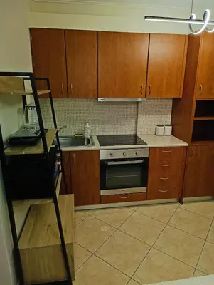a kitchen with wooden cabinets and a stove top oven at Aiolos GLYFADA super lux apartment in Athens