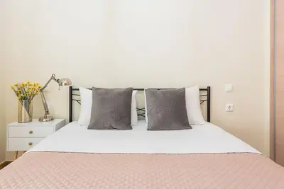 a bedroom with a white bed with pillows and a lamp at Cozy home near Stavros Niarchos in Athens