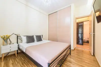 a bedroom with a white bed and a window at Cozy home near Stavros Niarchos in Athens