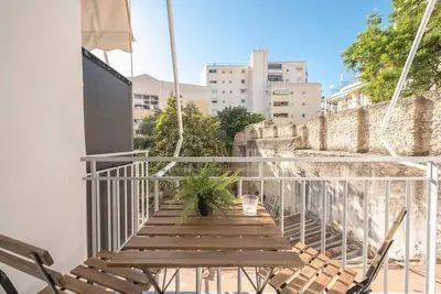 a balcony with a wooden bench and a plant at Cozy home near Stavros Niarchos in Athens