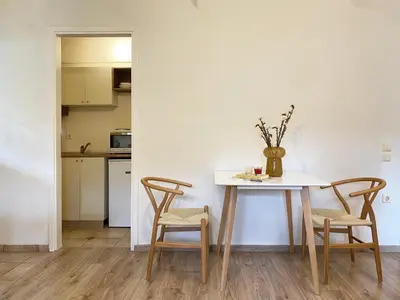 a dining room table with two chairs and a vase on it at Calm Cove One-Bedroom Home Glyfada in Athens