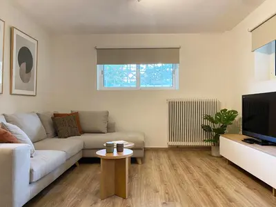 a living room with a couch and a tv at Calm Cove One-Bedroom Home Glyfada in Athens