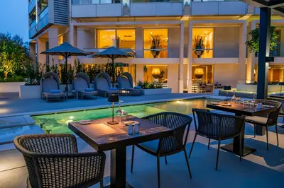 a restaurant with tables and chairs next to a swimming pool at Divani Escape - Adults Only in Athens