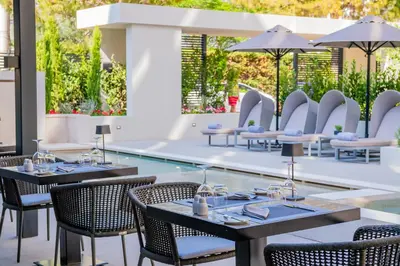 a restaurant with tables and chairs and a pool at Divani Escape - Adults Only in Athens