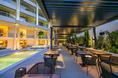 a restaurant with tables and chairs next to a swimming pool at Divani Escape - Adults Only in Athens