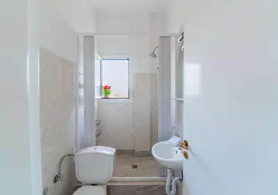 a white bathroom with a toilet and a sink at Amazing View Studio at Filopappou Hill in Koukaki! in Athens