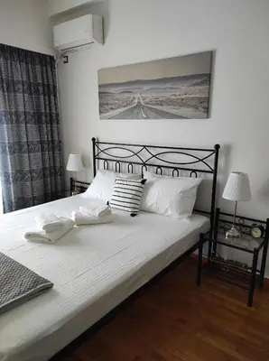 a bedroom with a black bed with white sheets and pillows at Cosy apartment on Dragon street in Athens