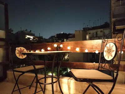 a table and chairs on a balcony with lights at Cosy apartment on Dragon street in Athens