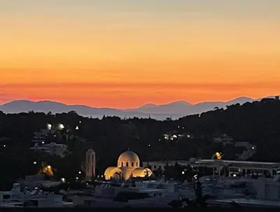 a view of a city at sunset with mountains in the background at Vouliagmeni Panoramic 200m2 Rooftop & 25m2 Loft in Athens