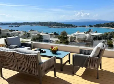 a balcony with a table and chairs and a view of the water at Vouliagmeni Panoramic 200m2 Rooftop & 25m2 Loft in Athens