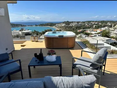 a patio with a hot tub and a table and chairs at Vouliagmeni Panoramic 200m2 Rooftop & 25m2 Loft in Athens