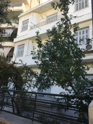 a white building with a tree in front of it at Simple & Spacious - Shared Accomodation in Athens