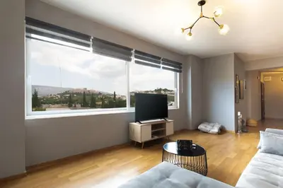 a living room with a tv and a large window at Stunning Acropolis view modern design house 2BD in Athens