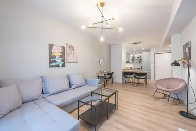 a living room with a blue couch and a dining room at Urban & Spacious Apartment in Athens