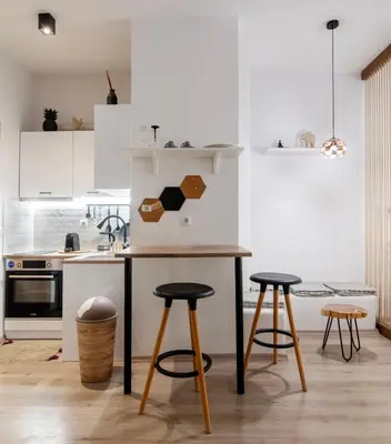 a kitchen with white cabinets and a table and stools at Acropolis Hidden Gem- The perfect Athenian Hideaway in Athens
